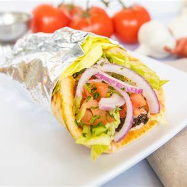 A Carolina Cheese Co. cafe wrap, partially unwrapped, filled with lettuce, tomatoes, and red onions.