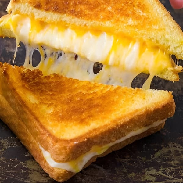 A grilled cheese sandwich from Carolina Cheese Co. pulled apart, showing gooey, melted cheese stretching.