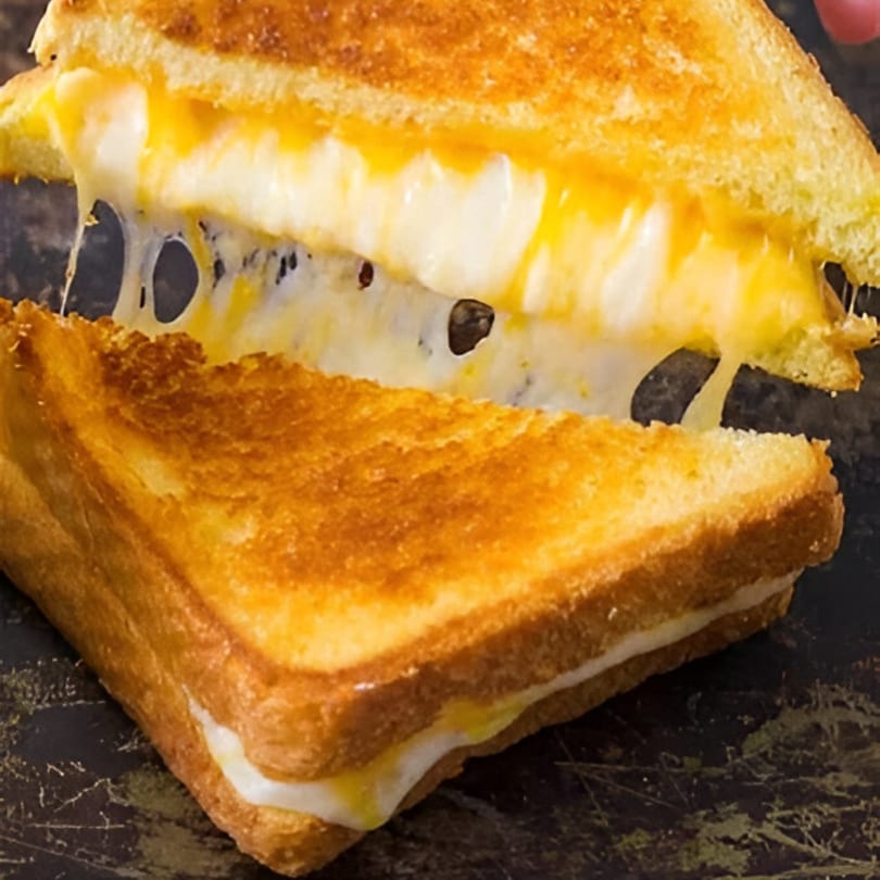 A grilled cheese sandwich from Carolina Cheese Co. pulled apart, showing gooey, melted cheese stretching.