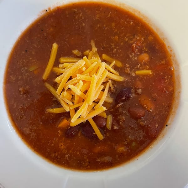 Hearty chili topped with shredded cheddar cheese in a white bowl from Carolina Cheese Co.